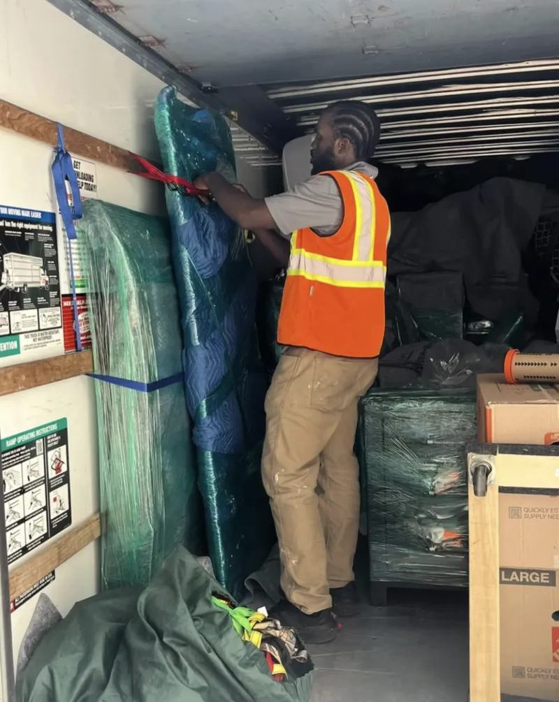 Express Moving Services mover handling protected furniture inside a moving truck