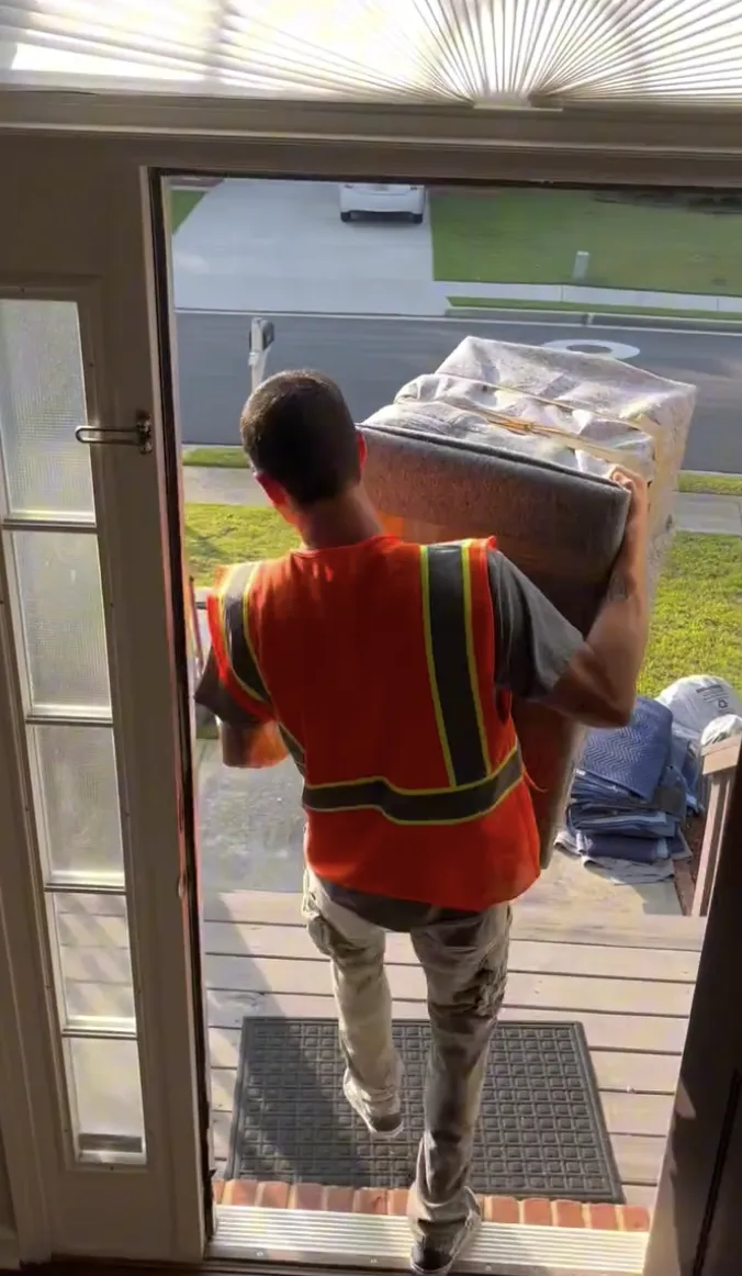 Express Moving Services mover carrying a wrapped chair through a doorway