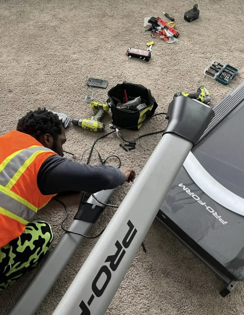 Express Moving Services worker assembling a treadmill at home
