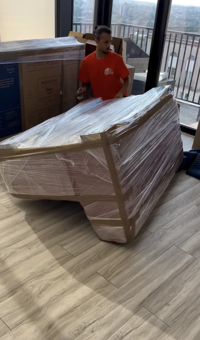Mover securing a wrapped sofa in an apartment