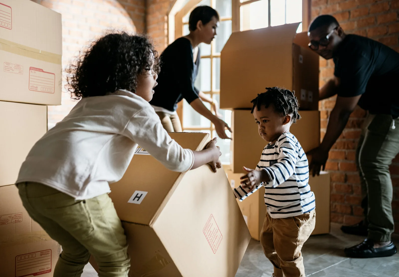 Family carrying cardboard moving boxes together at home